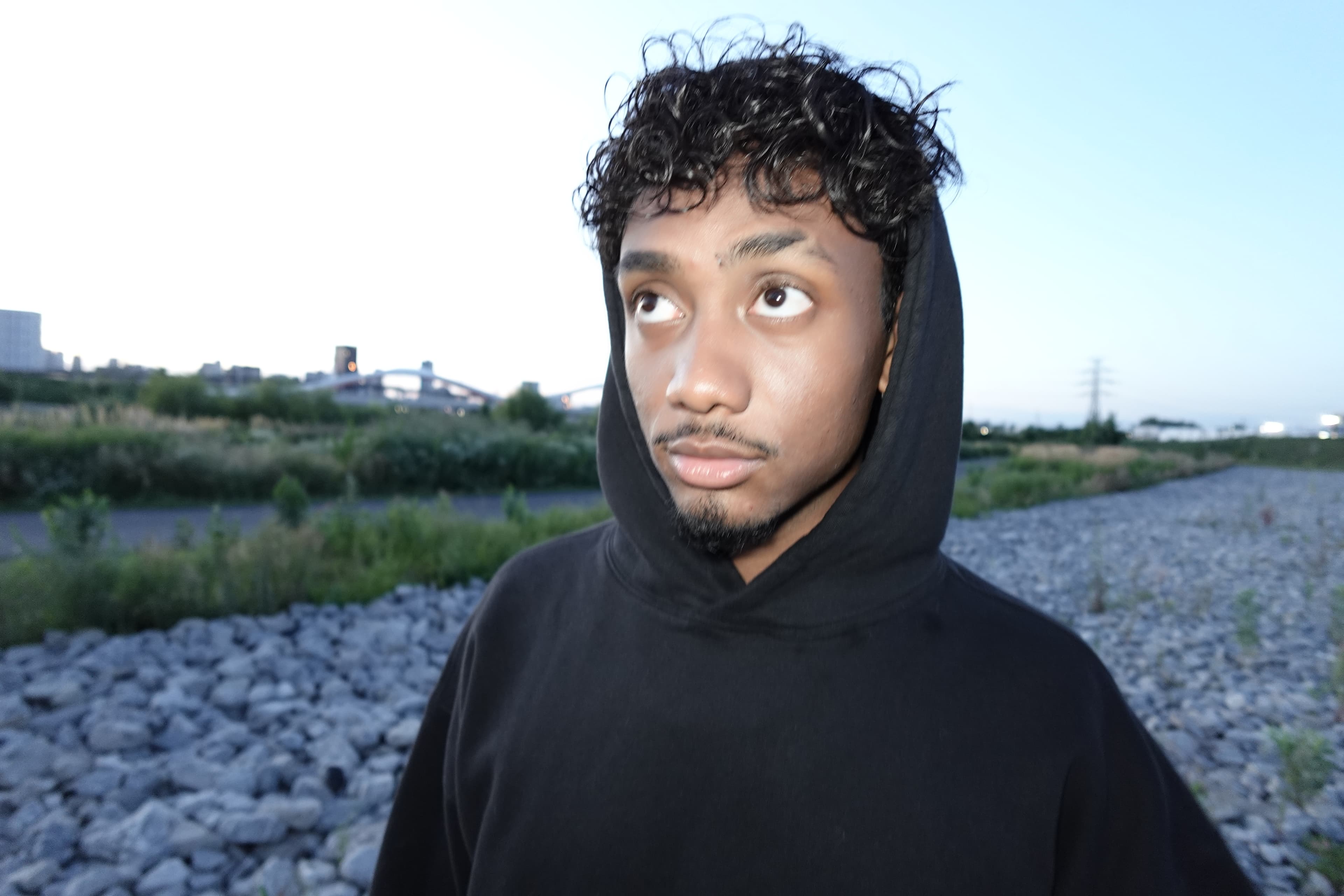 Marco Hope in a black hoodie at dusk by the rocky riverbank